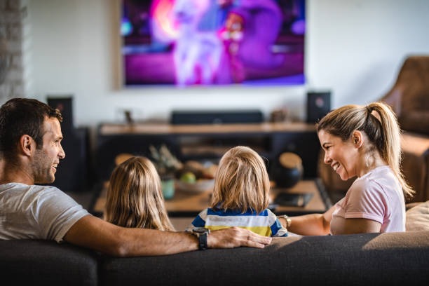 Família alegre no sofá assistindo TV